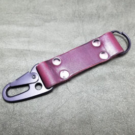 a purple handmade leather keychain on a gray surface.