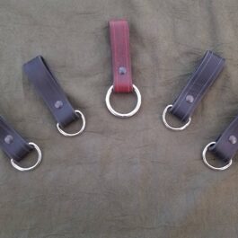 a group of four leather key chains on a bed.