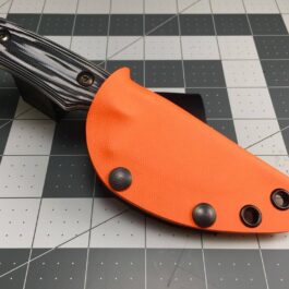 an orange and black knife laying on a tiled floor.