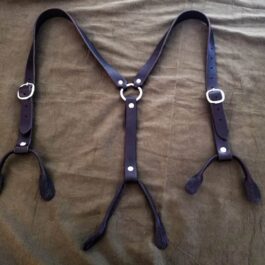 A pair of Handmade Leather Suspenders laying on a bed.