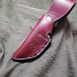 A red leather sheath for the Benchmade Hidden Canyon Hunter sitting on top of a gray cloth.