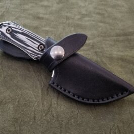 A Leather Sheath For The Benchmade Hidden Canyon Hunter with a black leather sheath on a green surface.