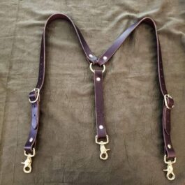 A pair of Handmade Leather Suspenders on a bed.