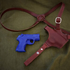 A blue gun and a red Handmade Leather Shoulder Holster.