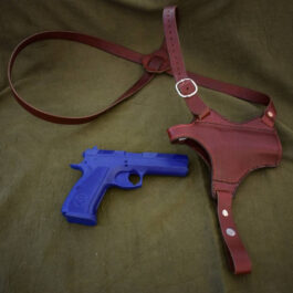 a blue and a red Handmade Leather Shoulder Holster laying on a bed.