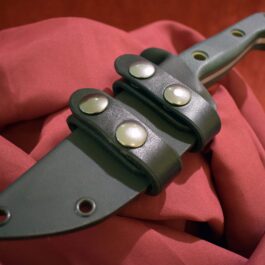 a Scout Style Benchmade Bushcrafter Kydex Sheath sitting on top of a red cloth.