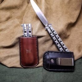 a Benchmade Balisong knife and a Leather Sheath For Benchmade Balisong Knives on a bed.