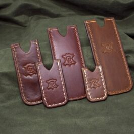 Three Handmade Leather Pocket Slips sitting on top of a green cloth.