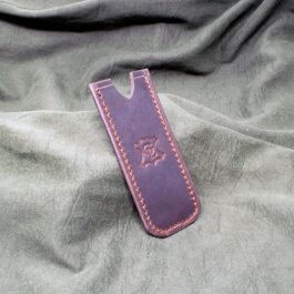 A Handmade Leather Pocket Slip sitting on top of a bed.