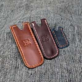 A couple of Handmade Leather Pocket Slips sitting on top of a gray cloth.