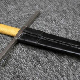 a Handmade leather Scabbard for the Albion Liechtenauer with a yellow handle laying on a gray surface.