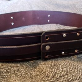 A close up of a Handmade Leather Space Wizard Belt on a bed.