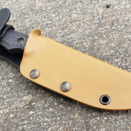 a knife with two holes in it laying on the ground.