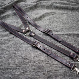A pair of Upgraded Leather Suspenders laying on top of a bed.