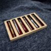 A wooden pen tray containing five pens.
