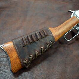 An Upgraded Handmade Leather Buttstock Cover with a leather case on a leather surface.