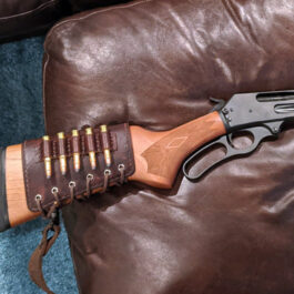 An Upgraded Handmade Leather Buttstock Cover is sitting on a leather couch.