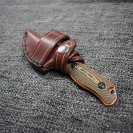 A Leather Scout Sheath for the Benchmade Hidden Canyon Hunter with a wooden handle on a carpet.