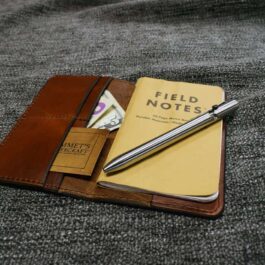A Field Notes Wallet on a bed.