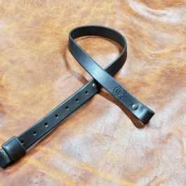A black Simple Rifle Sling laid on a brown leather cloth - Grommet's Leathercraft - renaissance clothing - renaissance art clothing - renaissance era clothing - leathercraft supplies - leathercraft accessories - leathercraft store near me - quality leather craft