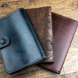 Three Field Notes Wallets sitting on top of a wooden floor.
