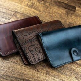 Three Field Notes Wallets sitting on top of a wooden table.