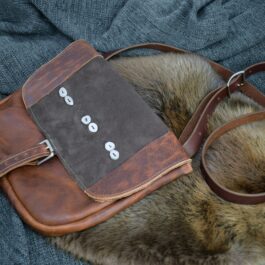A brown Arthur's Satchel sitting on top of a pile of fur.