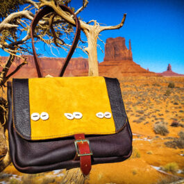 A yellow and black Arthur's Satchel hanging from a tree.