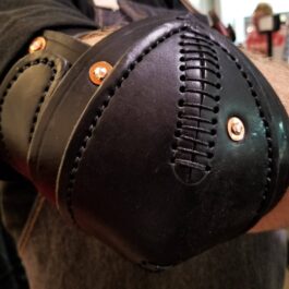 a close up of a person wearing a leather wrist guard.