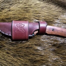 a knife with a leather sheath on top of it.