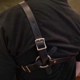 a man wearing a black shirt with a leather harness on his back.