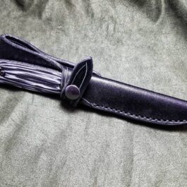 a knife with a black leather sheath on a gray cloth.