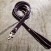 a leather leash with a metal hook on a bed.