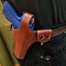 A man wearing a brown leather belt with a Handmade Leather Snap Loop Pancake Holster in his pocket.