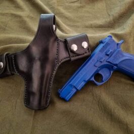A Handmade Leather Snap Loop Pancake Holster and a blue gun on a bed.