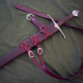 a purple leather sword laying on top of a bed.