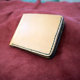 A close up of a Custom Handmade Bifold Leather Wallet on a red blanket.