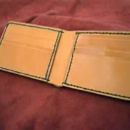 A Custom Handmade Bifold Leather Wallet sitting on a bed.