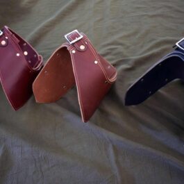 Three different Handmade Leather Gorget Style 1 bags on a bed.