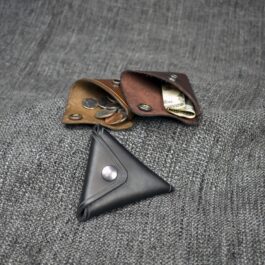 A Handmade Leather Coin Pouch sitting on top of a gray cloth.