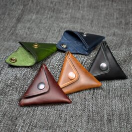 A group of four Handmade Leather Coin Pouches sitting on top of a gray cloth.