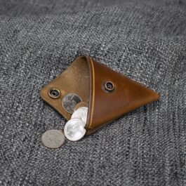 A Handmade Leather Coin Pouch with a few coins sticking out of it.