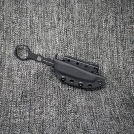 A Kydex Sheath for the Benchmade SOCP Dagger laying on top of a gray cloth.