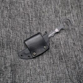 a black leather pocket knife laying on a gray cloth.
