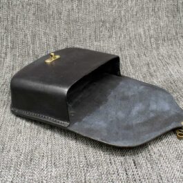 A Molded Leather Belt Pouch sitting on top of a gray couch.