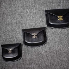Three Molded Leather Belt Pouches sitting on top of a gray carpet.