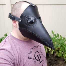 A man wearing a Handmade Leather Plague Doctor Mask with a black beak.