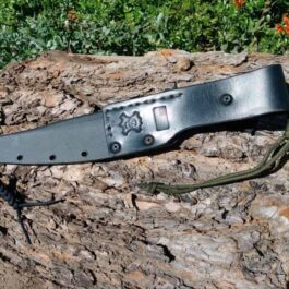 A Kydex Sheath for the TOPS Wild Pig Hunter laying on top of a tree stump.