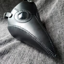 A Handmade Leather Plague Doctor Mask laying on a gray cloth.
