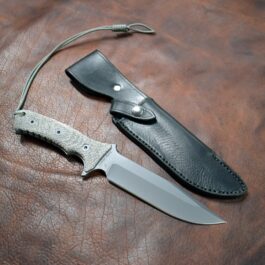 a knife and a knife sheath laying on a leather surface.